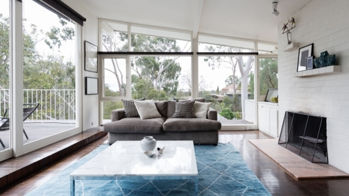 Mid century modern living room with huge windows to view the Australian treetops